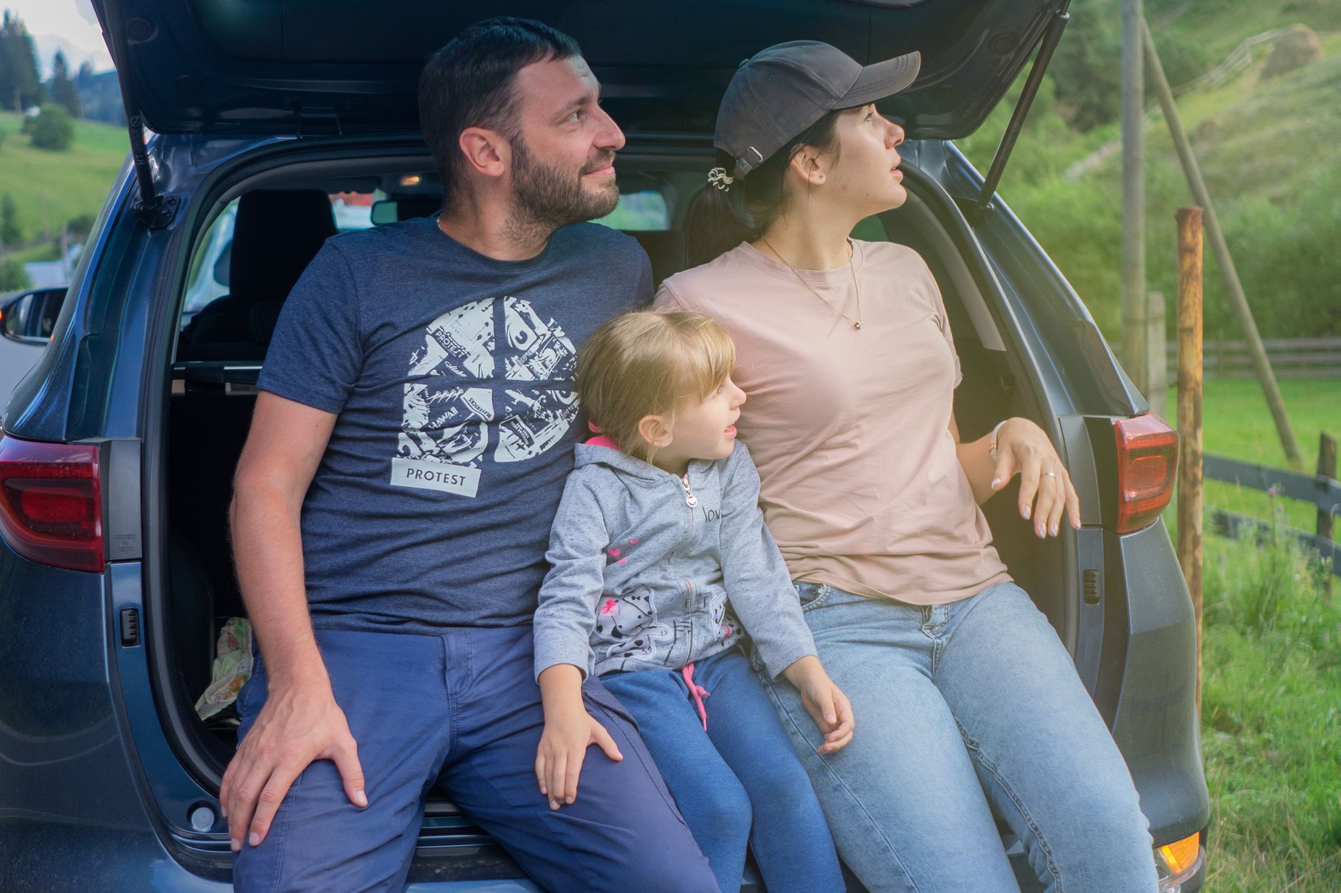 Família sentada no porta-malas aberto de um carro